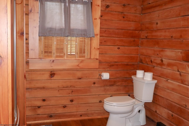 bathroom featuring toilet, wooden walls, and wood finished floors