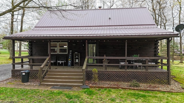 view of front facade featuring covered porch, log exterior, and metal roof