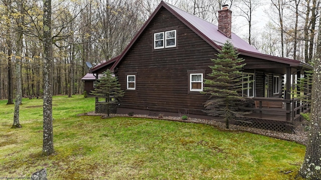 view of property exterior with metal roof, log siding, a chimney, and a lawn