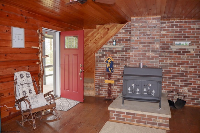 foyer entrance featuring a wood stove, hardwood / wood-style flooring, wood ceiling, and wood walls