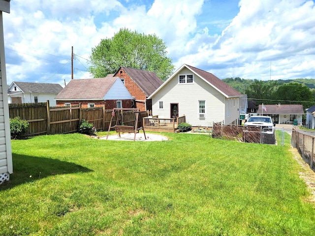 rear view of property featuring fence, a deck, and a lawn