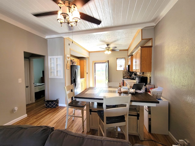dining space featuring a ceiling fan, baseboards, light wood finished floors, and crown molding