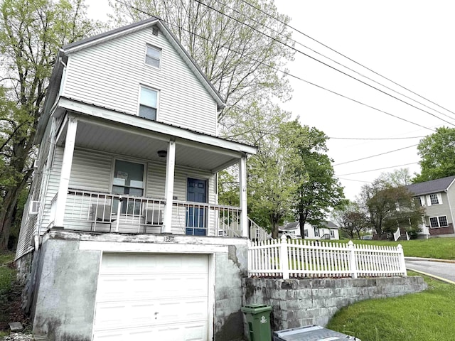 view of front facade with a porch, fence, and an attached garage