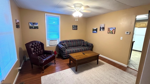 sitting room featuring cooling unit, baseboards, wood finished floors, and a ceiling fan