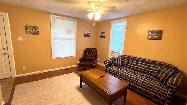 living room with cooling unit, wood finished floors, baseboards, and ceiling fan