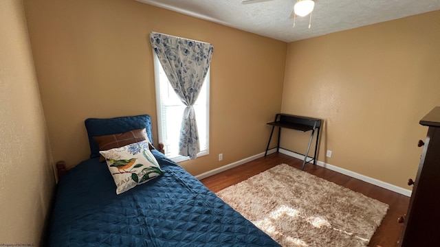 bedroom featuring a textured ceiling, wood finished floors, and baseboards