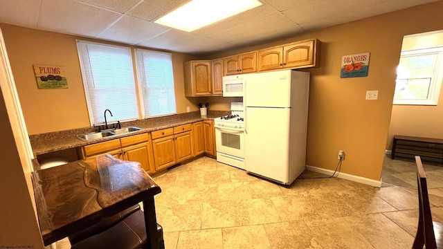 kitchen with a sink, white appliances, baseboards, and a wealth of natural light