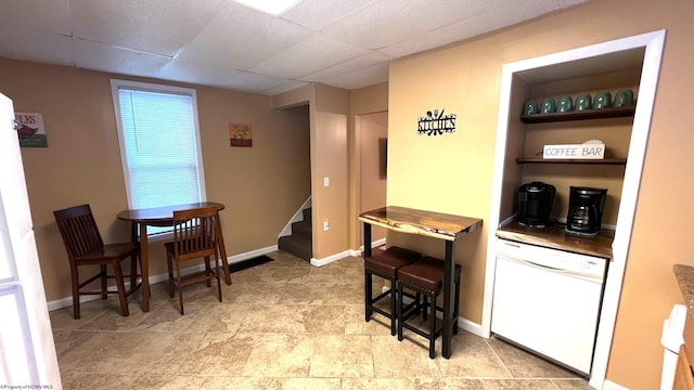 dining room with baseboards, stairs, and a drop ceiling