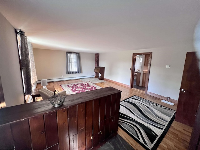 bedroom featuring wood finished floors, baseboards, and a baseboard heating unit