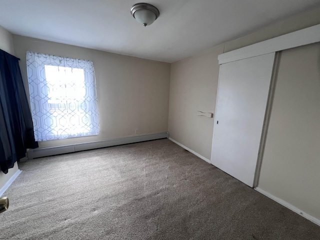 unfurnished bedroom with baseboards, a baseboard radiator, a closet, and carpet floors