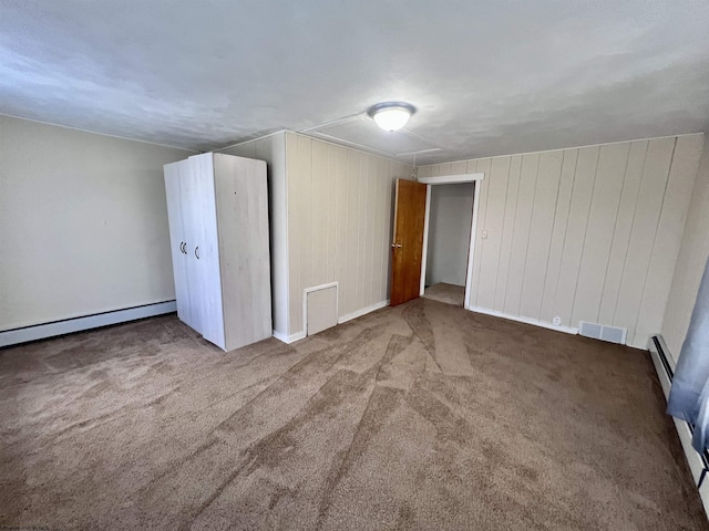 bonus room featuring carpet flooring, visible vents, baseboards, baseboard heating, and wooden walls