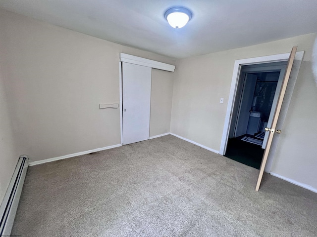 unfurnished bedroom with carpet flooring, a closet, baseboards, and baseboard heating