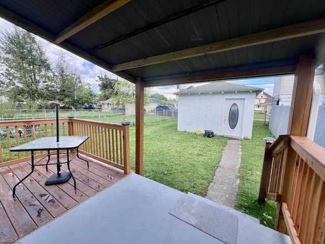view of patio / terrace featuring a storage unit, a deck, a fenced backyard, and an outbuilding