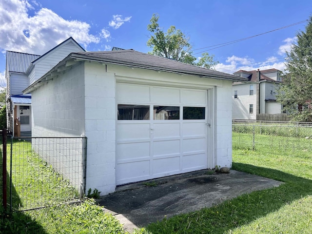 detached garage featuring fence and driveway