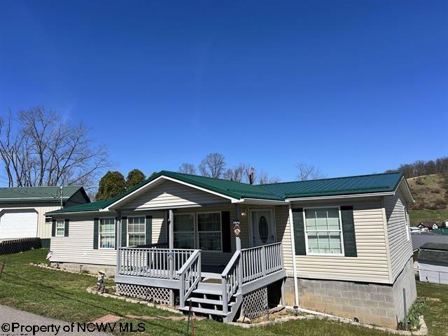 view of front of home featuring covered porch, crawl space, a front lawn, and metal roof