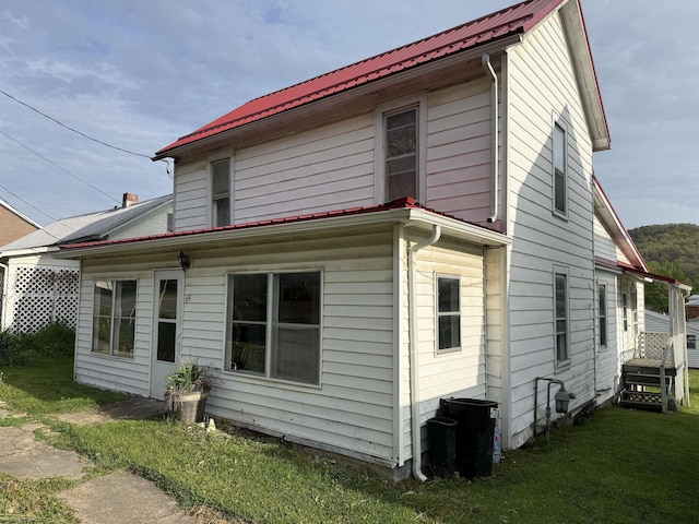 exterior space with metal roof and a lawn