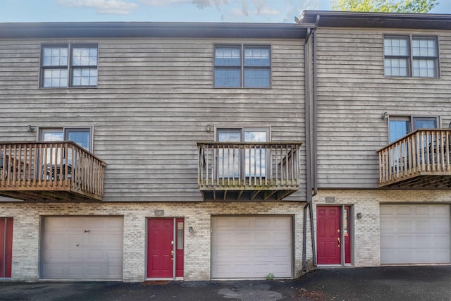 back of house featuring a balcony, an attached garage, and driveway