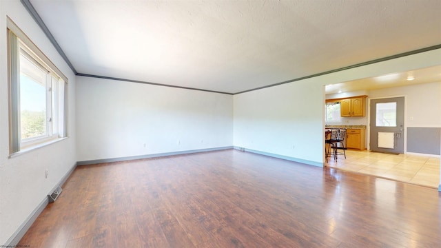 unfurnished living room with plenty of natural light, light wood-style floors, and baseboards