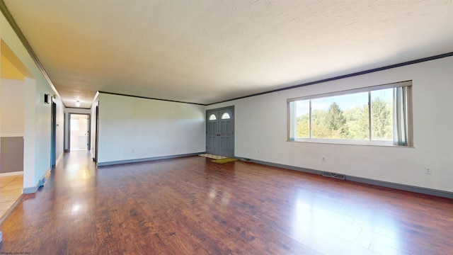 unfurnished living room with wood finished floors, ornamental molding, and baseboards