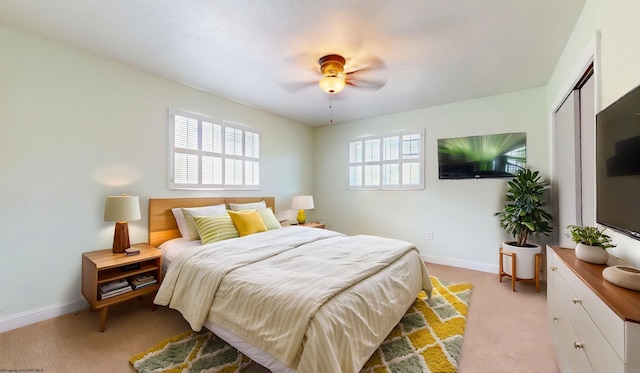 bedroom with light colored carpet, baseboards, a closet, and a ceiling fan