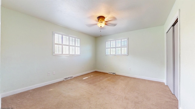 unfurnished bedroom with light carpet, baseboards, a closet, and a ceiling fan