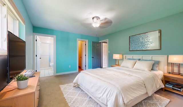carpeted bedroom featuring ensuite bathroom, baseboards, and a ceiling fan