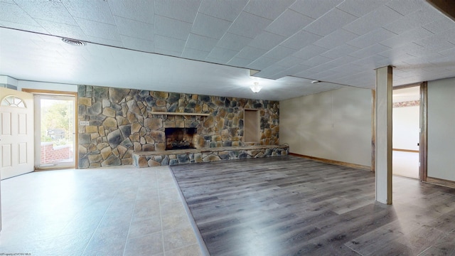 basement featuring a stone fireplace, wood finished floors, and baseboards