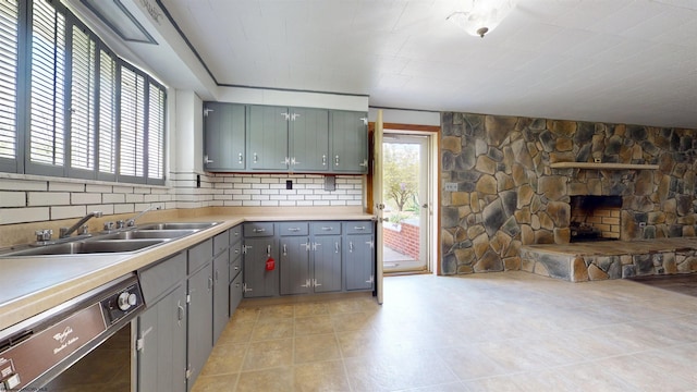 kitchen featuring dishwasher, a sink, gray cabinets, light countertops, and open floor plan