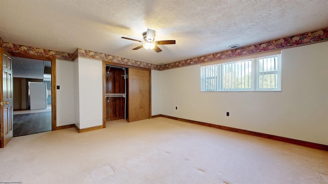 unfurnished bedroom with light carpet, a closet, baseboards, a textured ceiling, and a ceiling fan