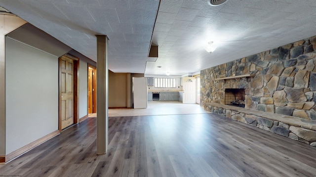 unfurnished living room with wood finished floors, baseboards, and a fireplace