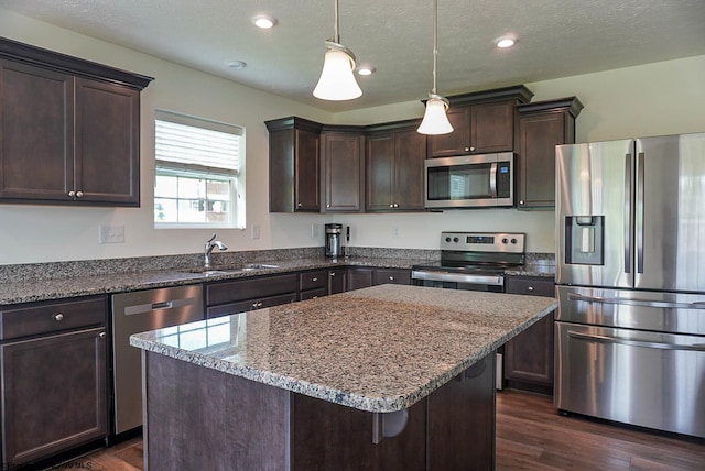 kitchen featuring stainless steel appliances, a sink, dark brown cabinetry, dark wood-type flooring, and recessed lighting