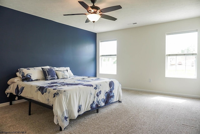 carpeted bedroom featuring baseboards and a ceiling fan