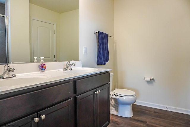full bathroom featuring toilet, wood finished floors, baseboards, and double vanity