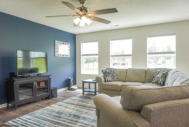 living area with plenty of natural light, baseboards, a ceiling fan, and a textured ceiling