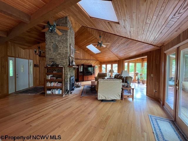 677 Dylan Rd, Elkins, WV 26241 - living room with a skylight, a ceiling fan, wood ceiling, wood walls, and a large fireplace