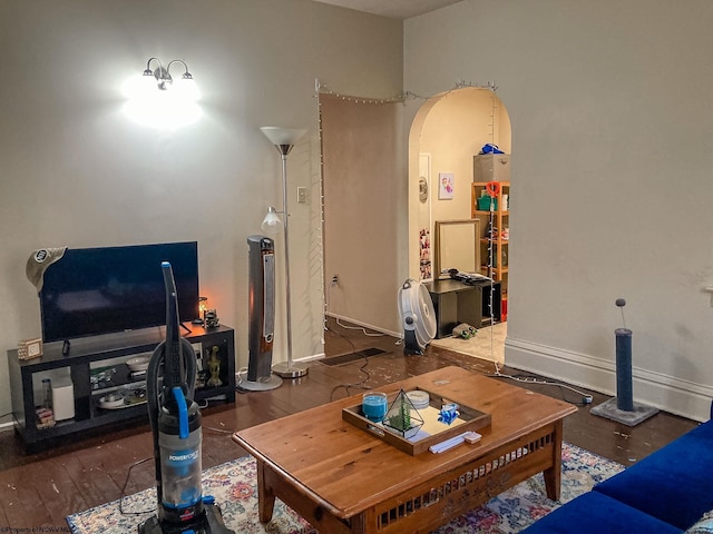 living room featuring arched walkways, baseboards, and wood finished floors