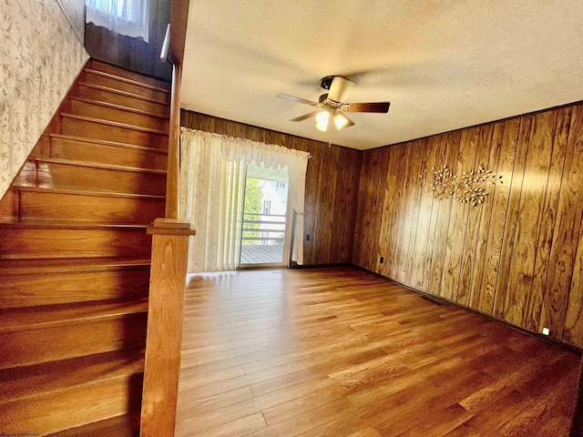 303 Morgantown St, Kingwood, WV 26537 - empty room with a ceiling fan, wood finished floors, stairs, a textured ceiling, and wood walls