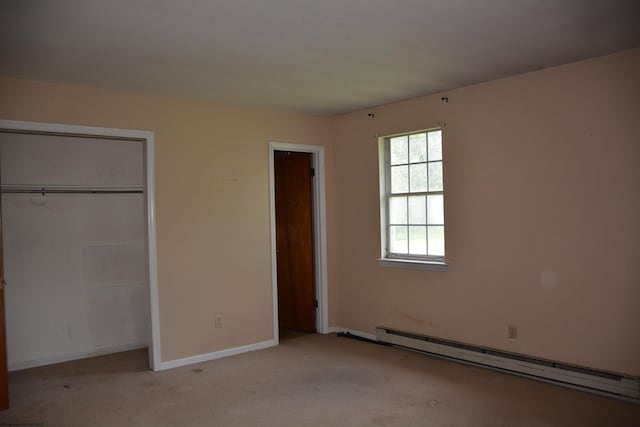 unfurnished bedroom featuring a baseboard heating unit, carpet, baseboards, and a closet
