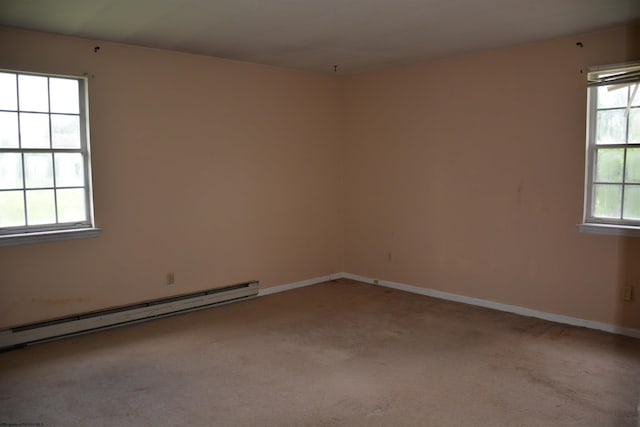 spare room with baseboard heating, carpet flooring, and baseboards
