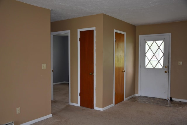 carpeted entrance foyer featuring baseboards and a textured ceiling