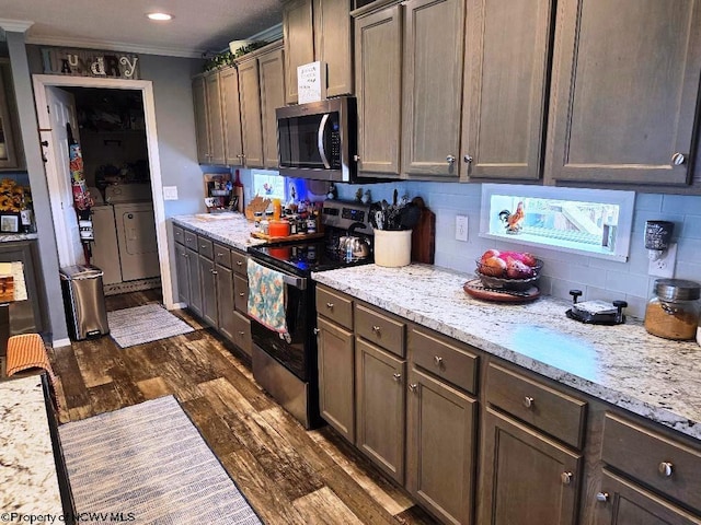 kitchen with stainless steel appliances, washing machine and clothes dryer, dark wood-style flooring, crown molding, and backsplash