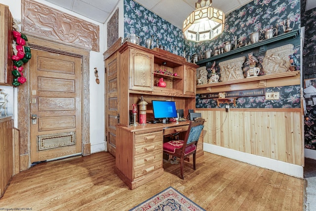 office area with wallpapered walls, light wood-style flooring, built in study area, a wainscoted wall, and wooden walls