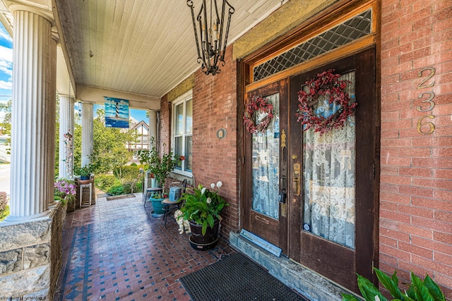 doorway to property with covered porch and brick siding