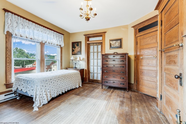 bedroom featuring light wood-type flooring, a chandelier, and a baseboard radiator