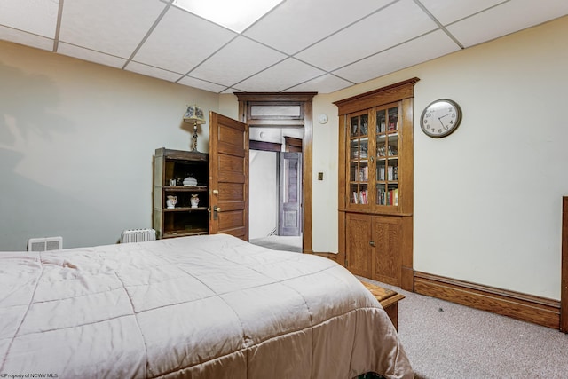 carpeted bedroom featuring a paneled ceiling and baseboards