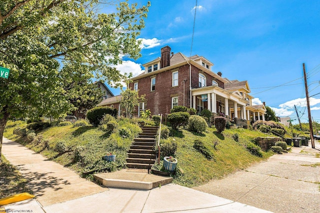 view of property exterior featuring stairway, brick siding, and a chimney