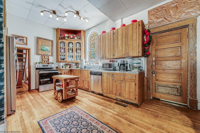 kitchen featuring appliances with stainless steel finishes, light wood finished floors, light countertops, and brown cabinetry