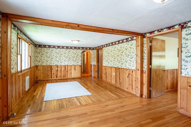22 N Euclid Ave, Thomas, WV 26292 - empty room featuring wallpapered walls, hardwood / wood-style flooring, wainscoting, wood walls, and a textured ceiling