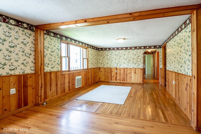 22 N Euclid Ave, Thomas, WV 26292 - unfurnished room featuring hardwood / wood-style flooring, wallpapered walls, a wainscoted wall, a textured ceiling, and wood walls
