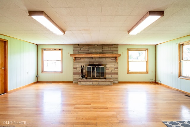 22 N Euclid Ave, Thomas, WV 26292 - unfurnished living room featuring light wood-style floors, healthy amount of natural light, a fireplace, baseboards, and wooden walls